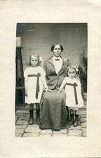 Photo card of a strict woman with two sad girls