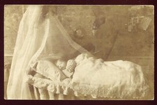 Old postcard photo card. Baby in his old wooden crib. 1906
