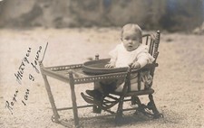 Old postcard photograph baby in his child's chair in the garden
