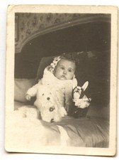 Baby child sitting on bed with plush toys - antique amateur photo year. 1940