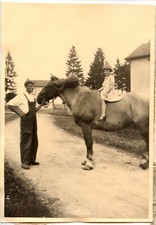 Man holding horse bridle with little girl - old photo year. 1930