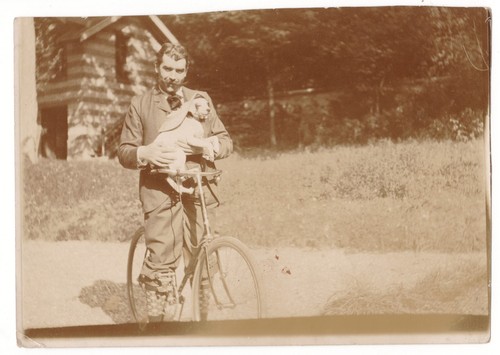 Man cycling holding his dog