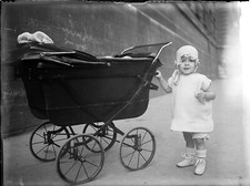 Portrait child standing next to pram - old photo negative glass year. 1920