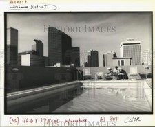 1990 Press Photo Roger Ploum sits by the pool atop Julia Place apartments