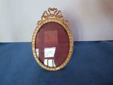 old oval bronze and brass photo frame topped with a knot