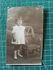 UG328 circa 1920 girl standing near a rattan chair