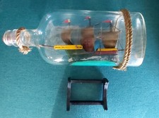 Model boat sailboat on the sea in glass bottle with its wooden stand