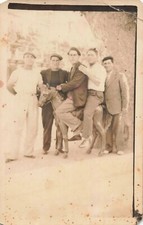 Old postcard photography scene of life group of men on a wooden horse riding