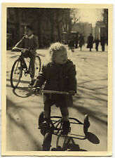 Little girl on bike tricycle city street - old photo year. 1950