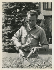 USA, A man cuts his hedge while listening to his portable radio, print run