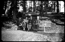 Women and young man sitting forest wood bench - old photo negative year. 1930 1940