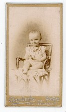 PHOTO Mignonnette, smiling child sitting wicker armchair by Chamberlin Paris