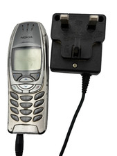 Nokia 6310i mobile phone connected to a charger with a UK-style plug.